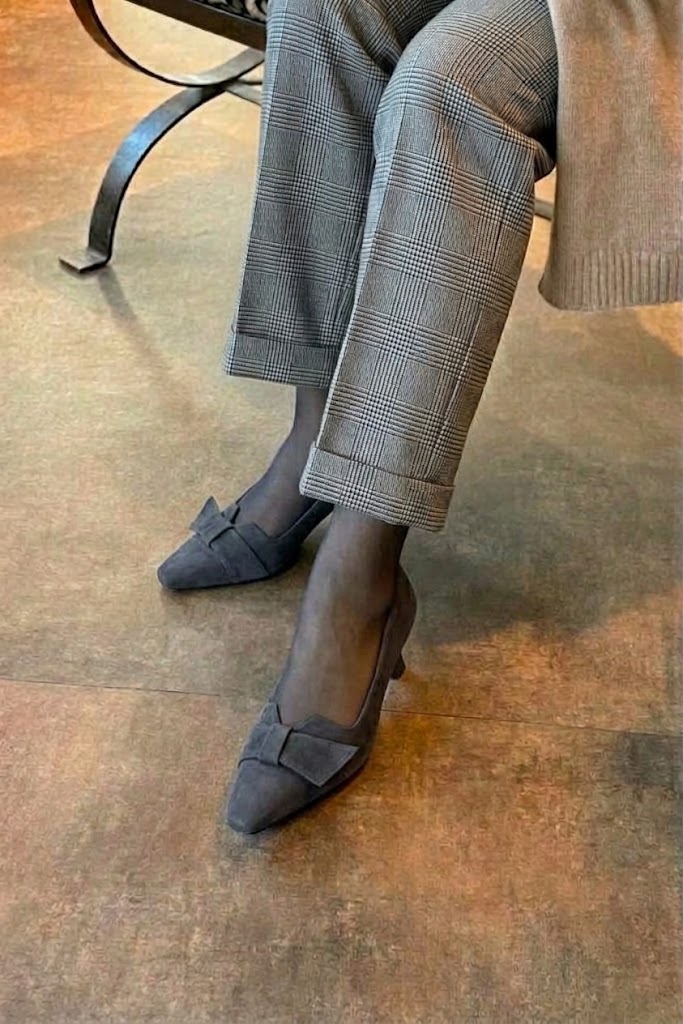 Women's charcoal gray bow pumps with almond toe and mid spool heel - Worn view
